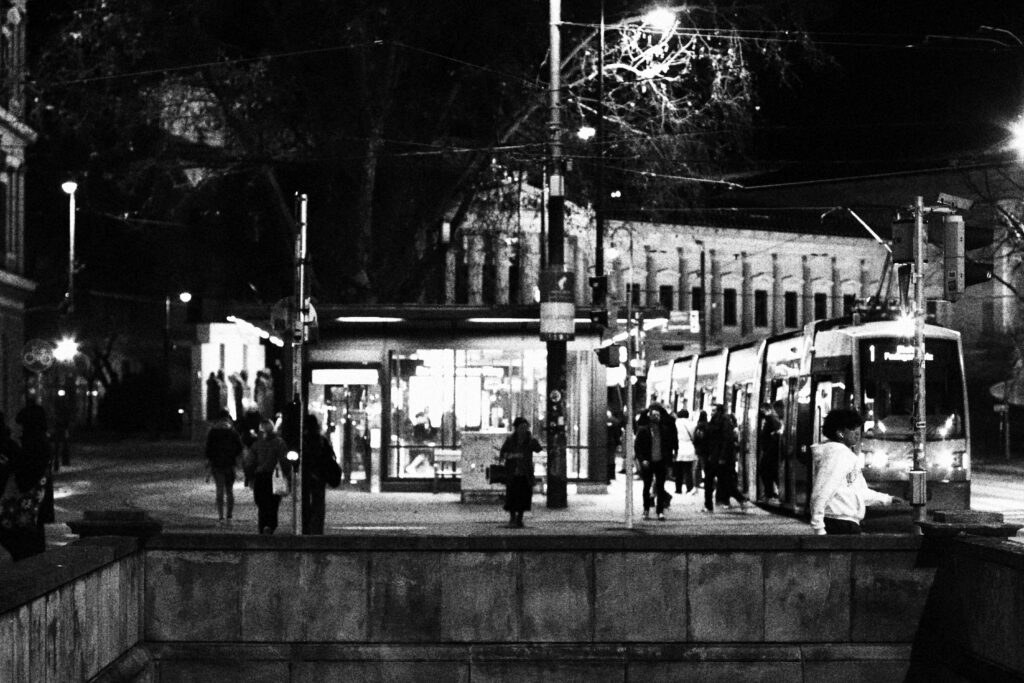 Ludzie czekający na przystanku tramwajowym.