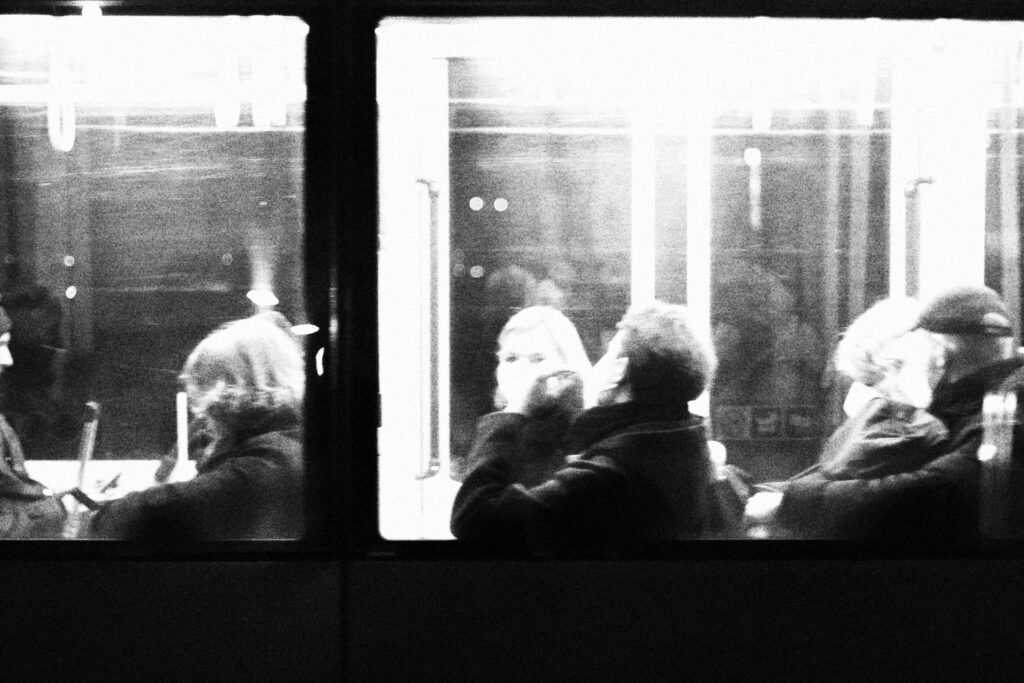 Pasażerowie widoczni przez okno tramwaju.